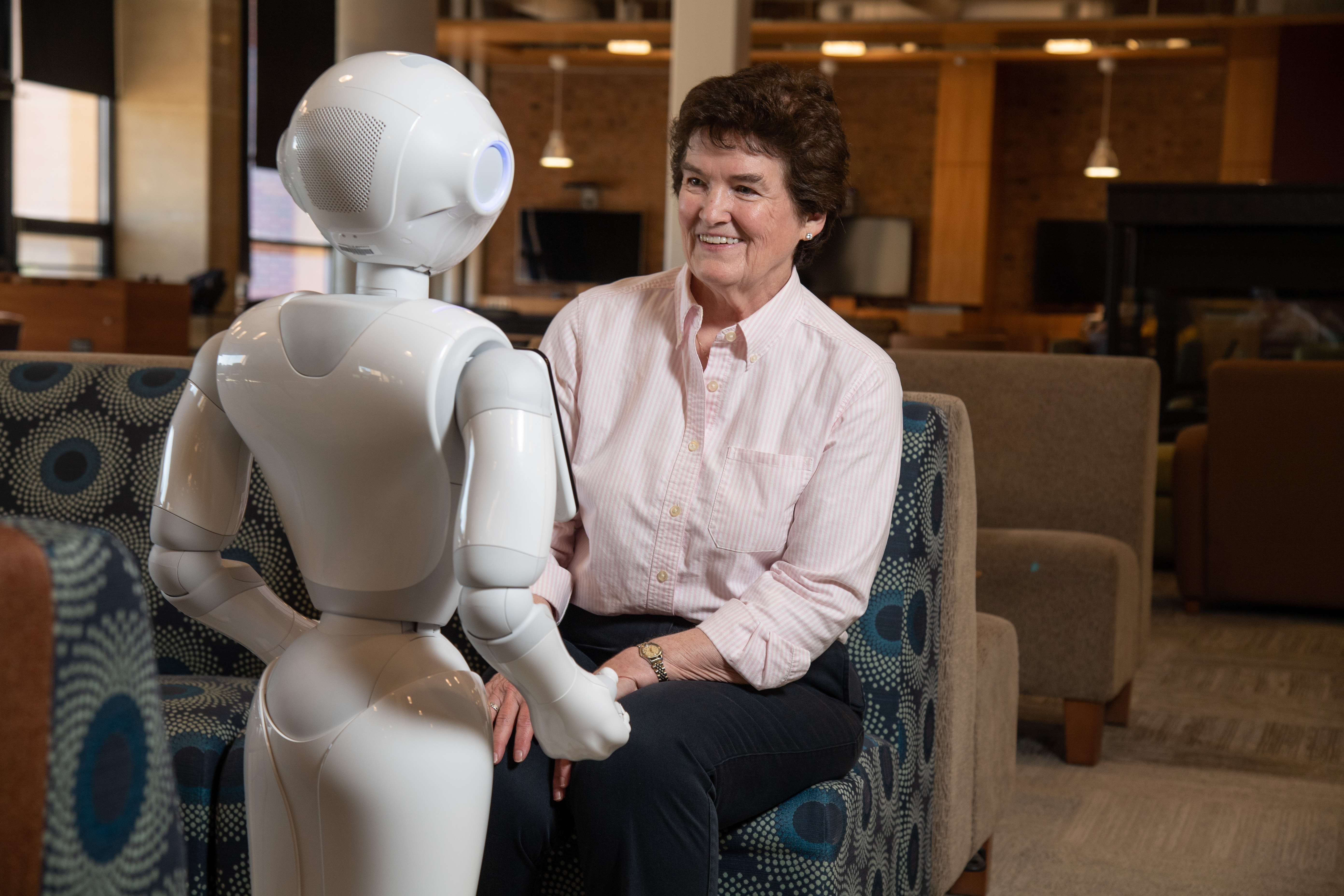 An older woman smiling at a robot.
