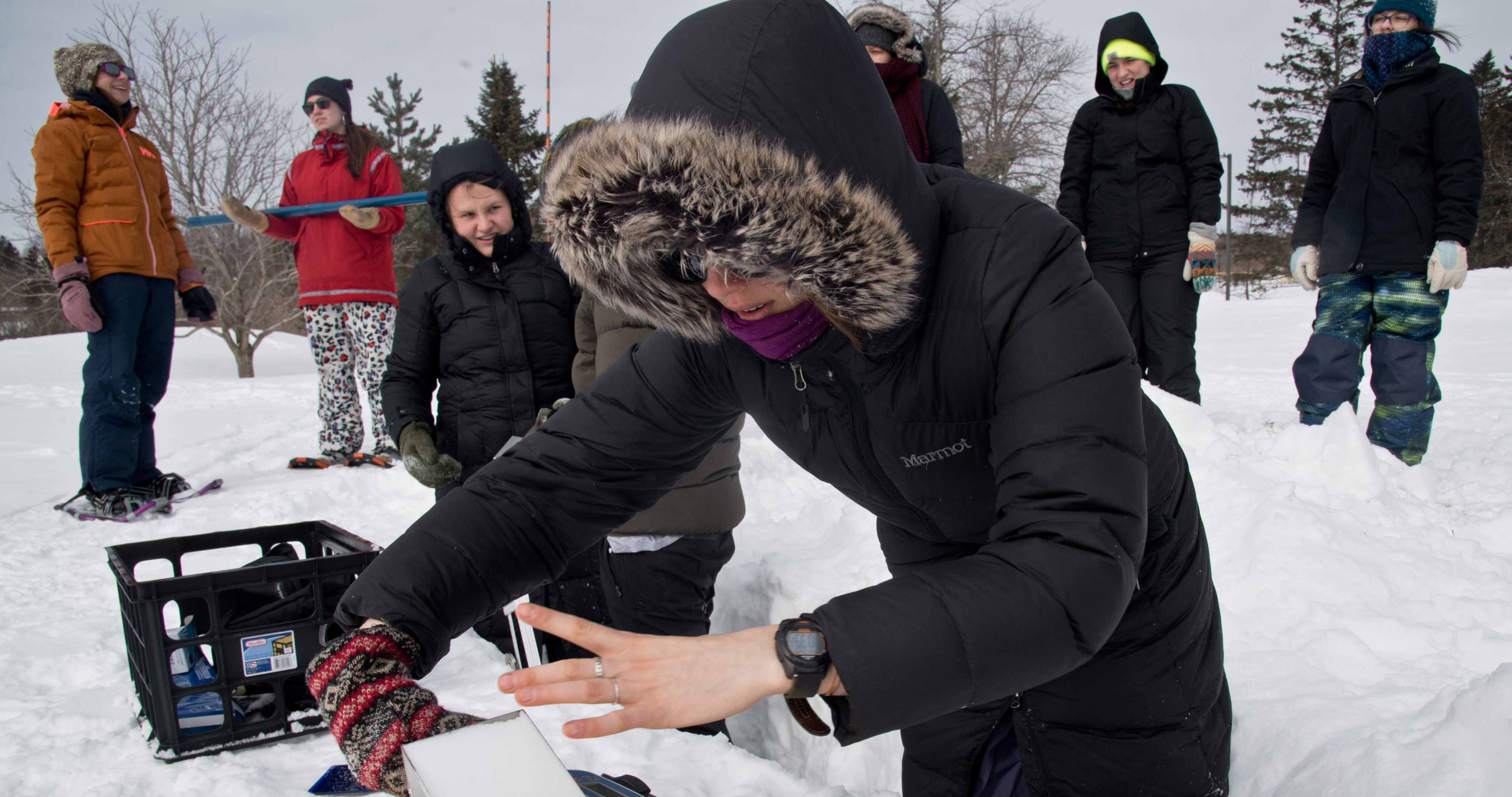 A student in the snow collecting a sample