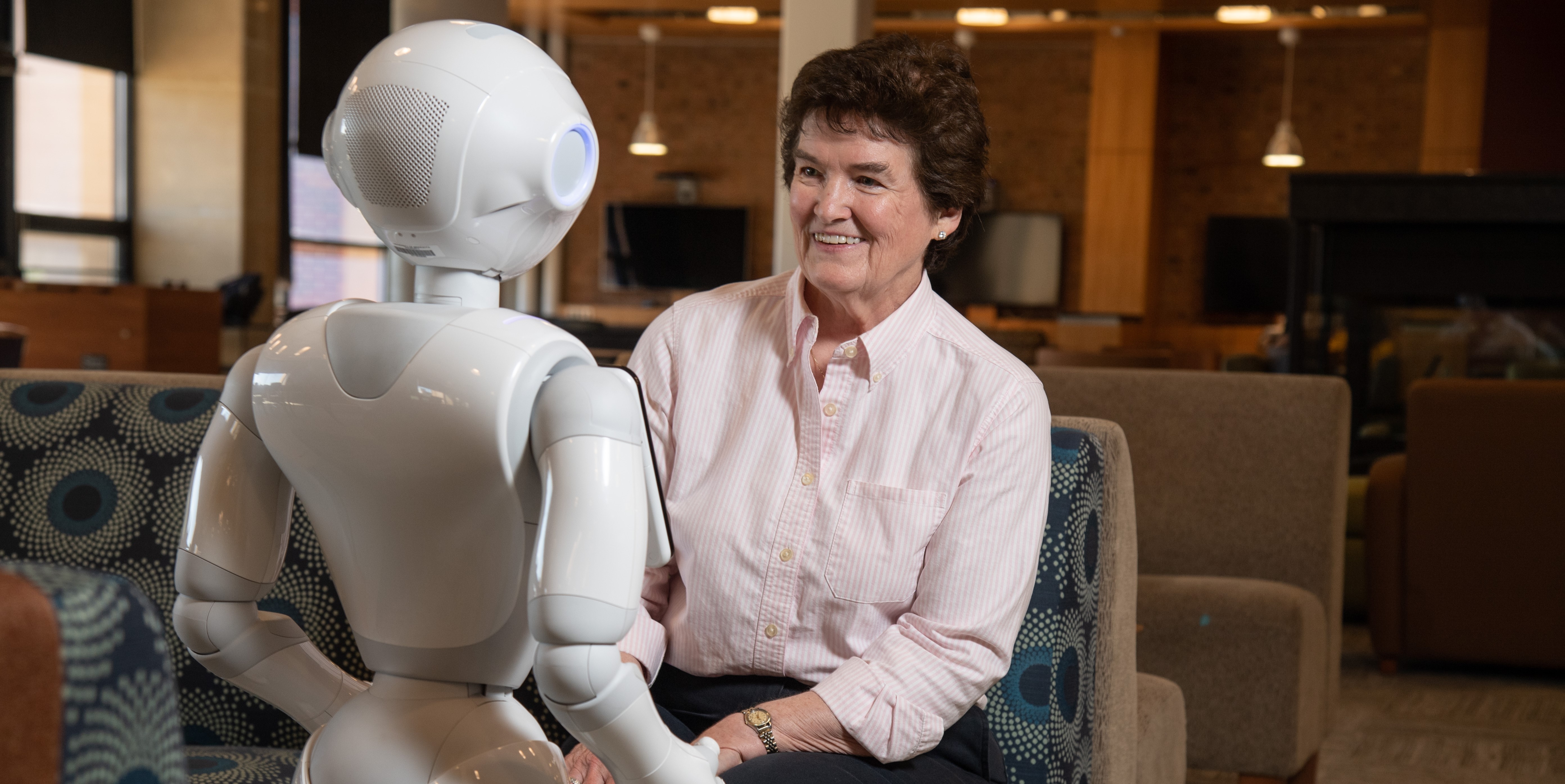 A seated woman chats with Pepper the robot