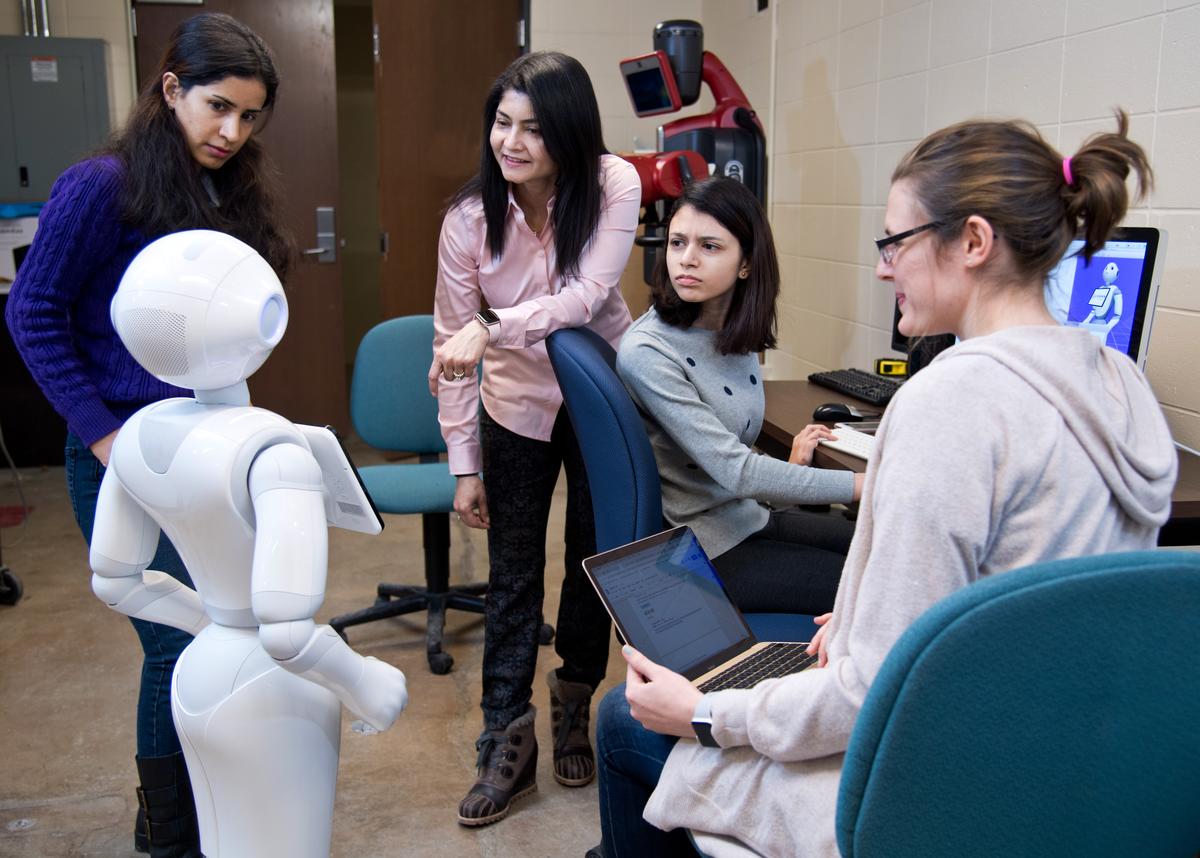 A group of students looking at a robot.
