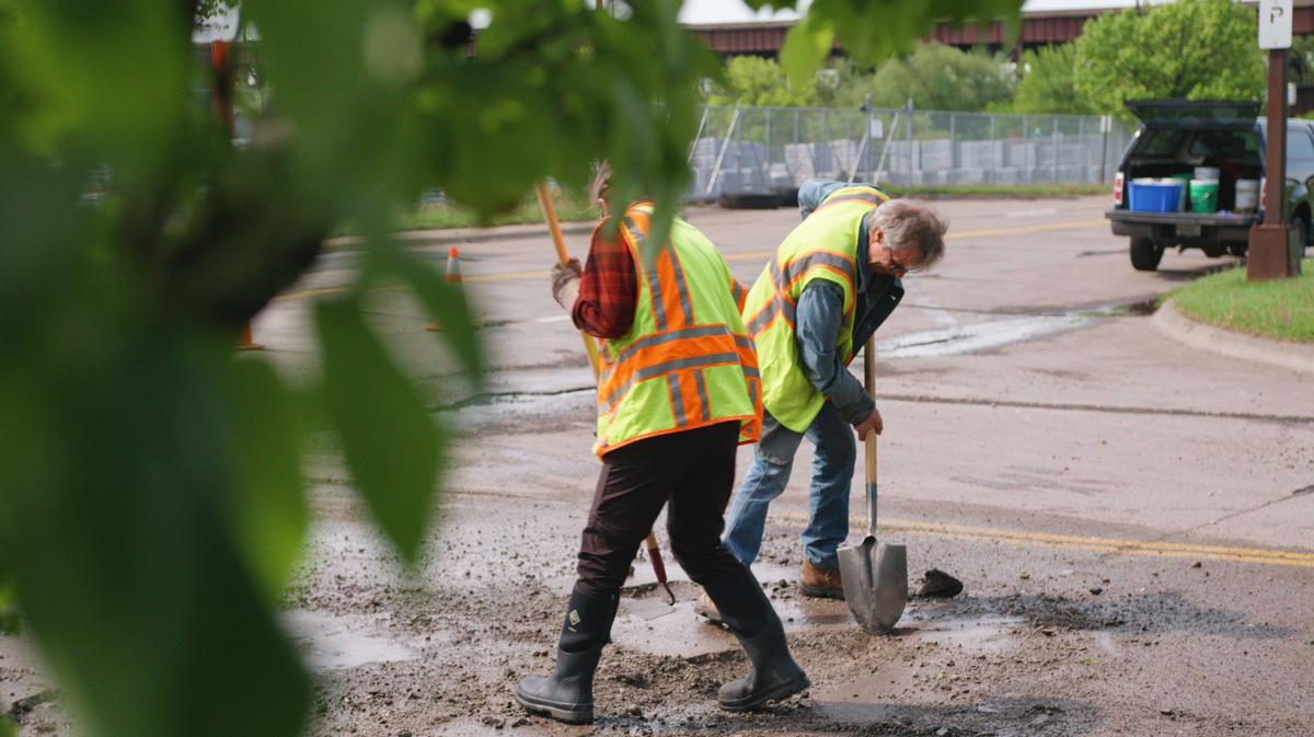 Two workers in hi-viz gear repairing potholes